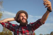 Uomo con barba e cappello si fa un selfie